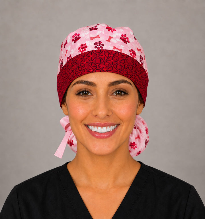 Valentine puppy paws and bones ponytail surgical cap right three-quarter angle showing gathered ponytail pouch of pink and red paw prints and dog bones with pink ribbon bow