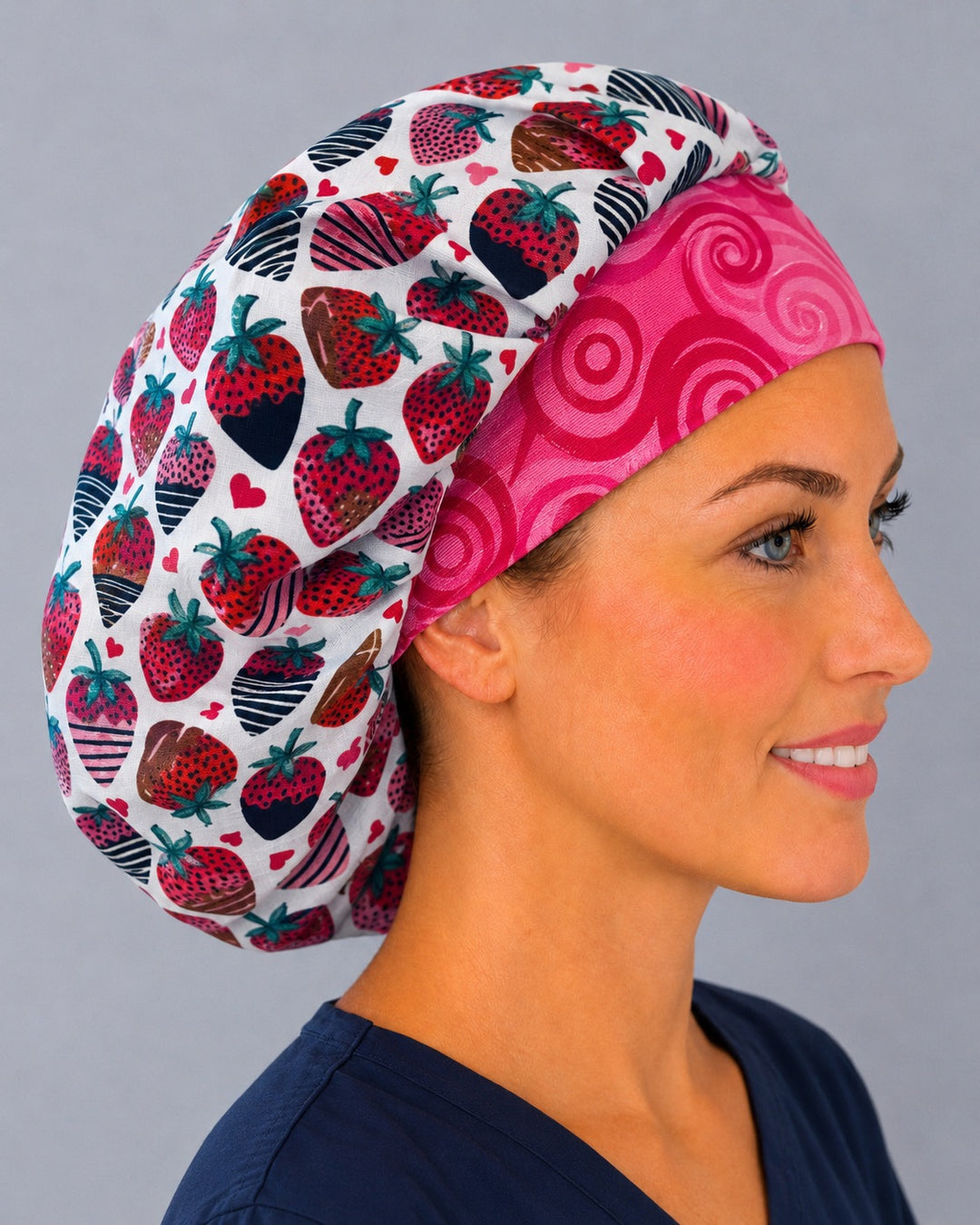 Side view of the Valentine strawberry bouffant surgical hat — chocolate-dipped berry print with hot pink swirl contrast band, roomy cotton cap