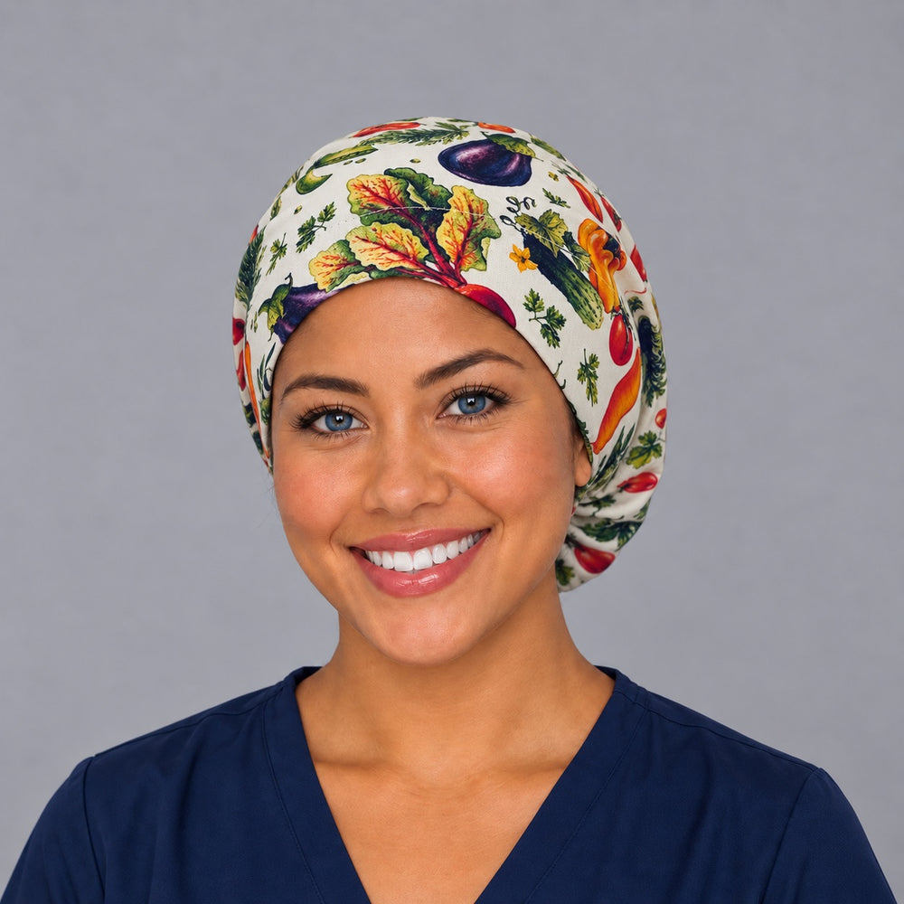 Woman wearing a vegetable garden Euro scrub cap, front view — tomatoes, peppers and greens on white, adjustable surgical hat for nurses