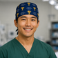 Surgeon wearing a navy "Voted #1 Surgeon by My Patients" scrub cap with gold trophies, front view in the OR — handmade-in-USA gift for surgeons from OR World.