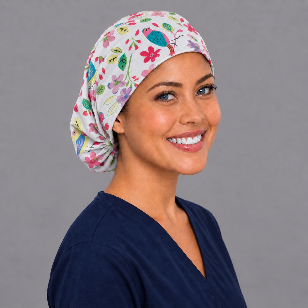 Watercolor bird Euro scrub cap, right angled smiling view — pink and violet blossom print for OR nurses and surgical techs