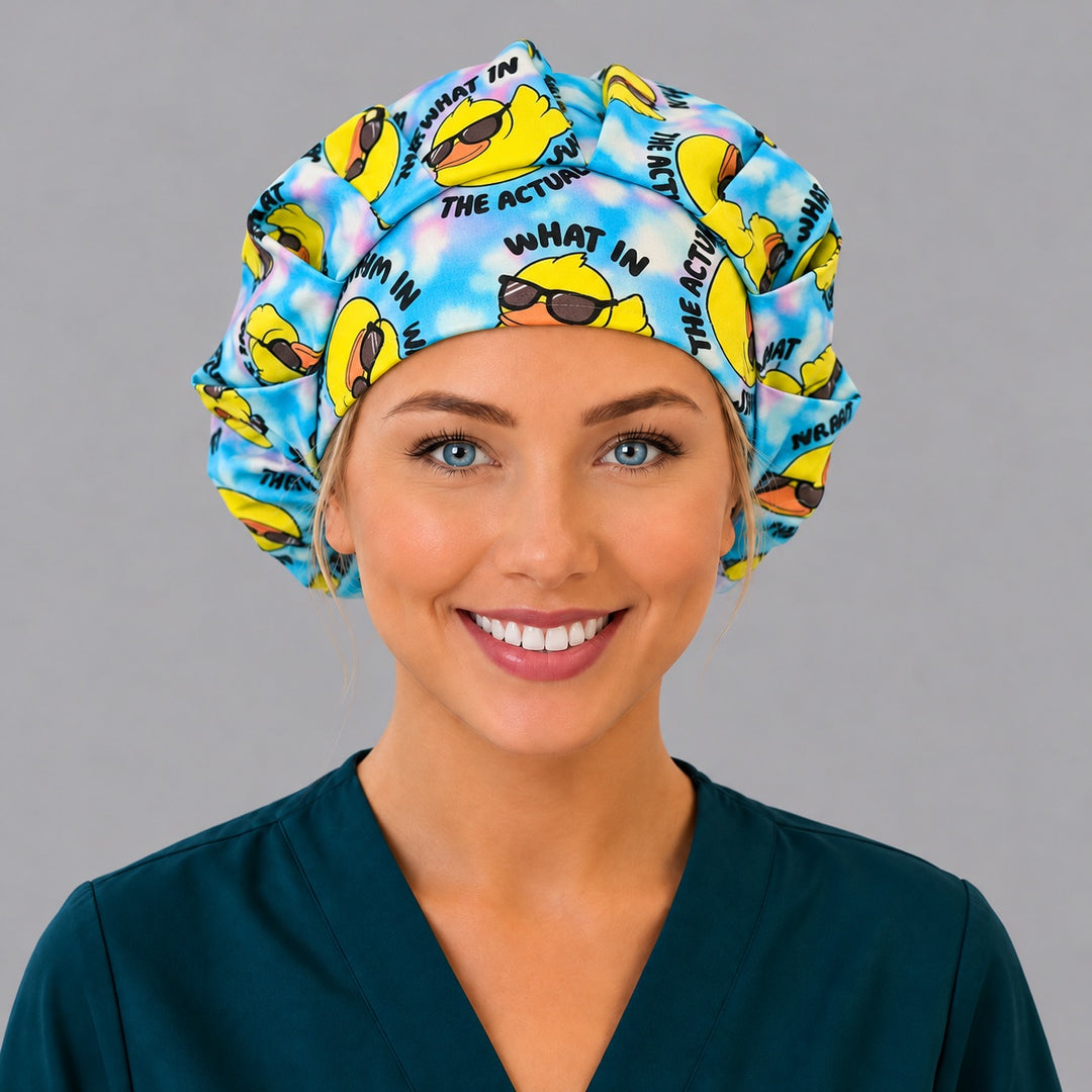 Front view of a smiling nurse in the What in the Actual duck bouffant scrub cap, with a sunglasses rubber duck centered on the forehead band