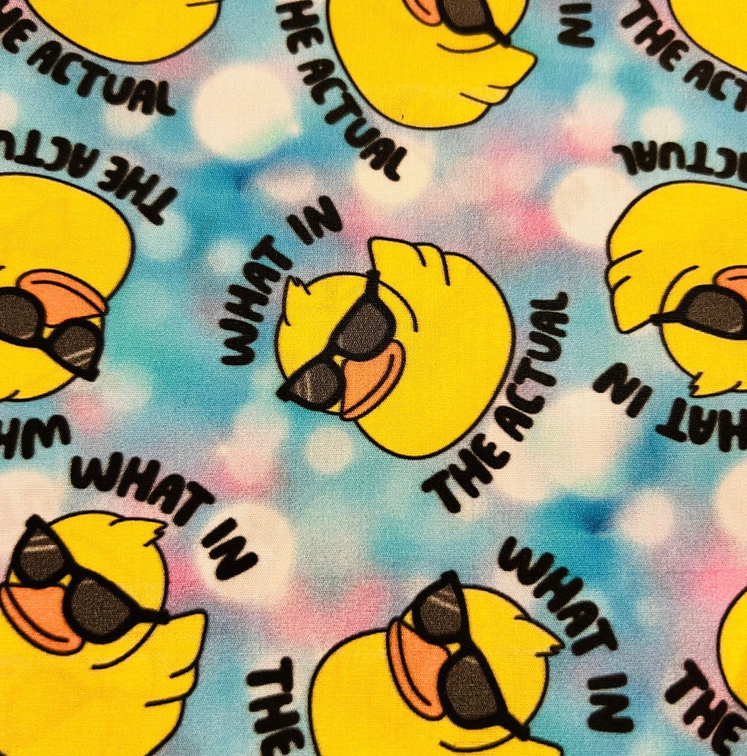 Fabric detail of the What in the Actual Duck scrub cap — close-up of sunglasses ducks on pastel tie-dye cotton