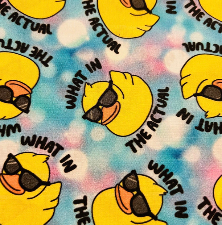 Fabric detail of the What in the Actual Duck scrub cap — close-up of sunglasses ducks on pastel tie-dye cotton