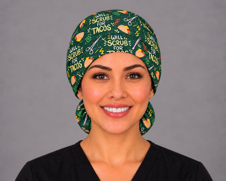 Smiling nurse in black scrubs wearing a Will Scrub for Tacos ponytail scrub cap, front view with the yellow slogan across the forest green crown