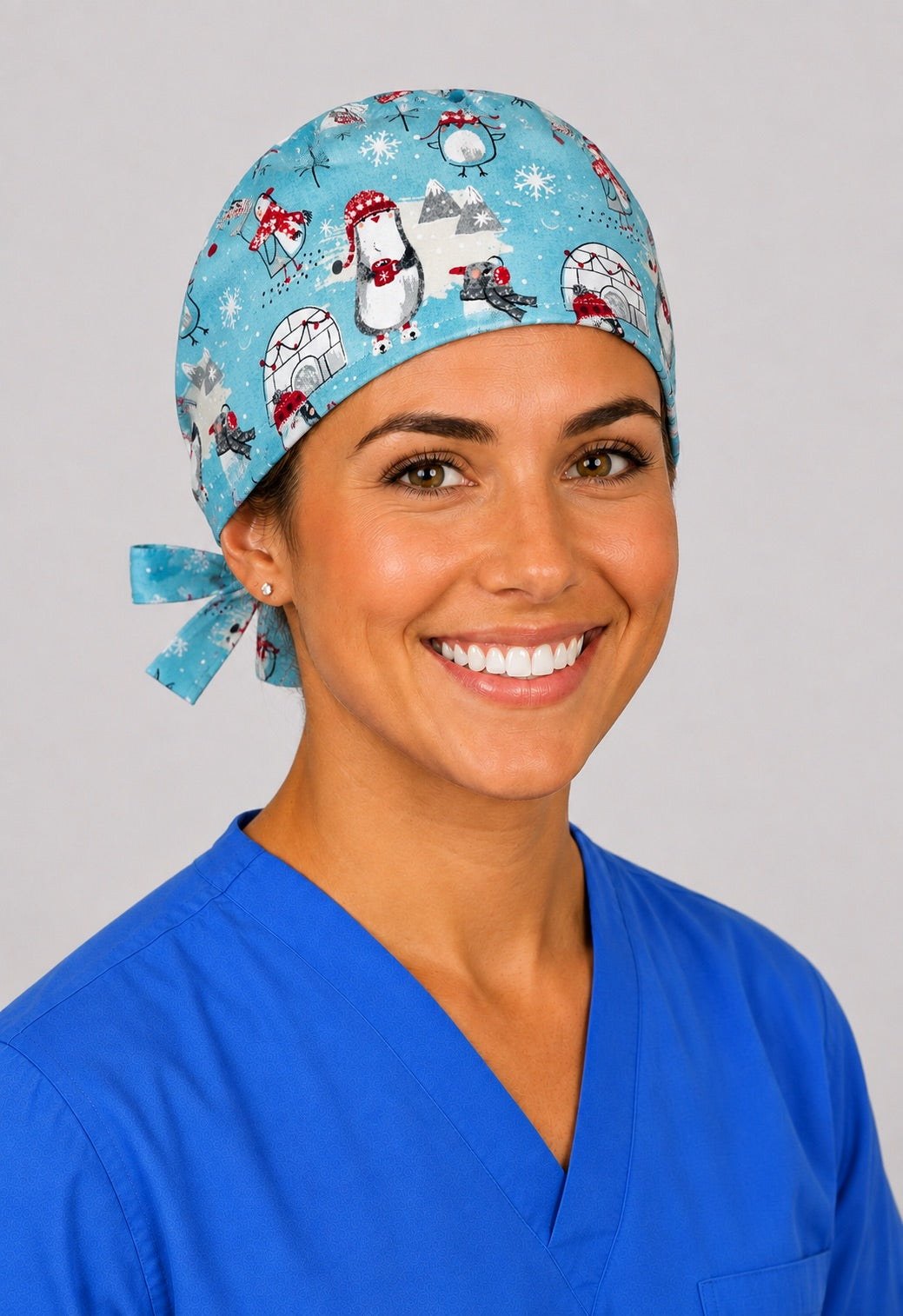 Angled front view of winter penguin snowflake scrub cap in aqua, handmade holiday nurse hat