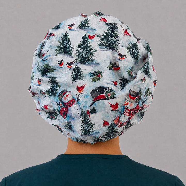 Woman wearing a winter snowman bouffant scrub cap, front view — snowmen, cardinals and pines with red buffalo plaid band, adjustable women&