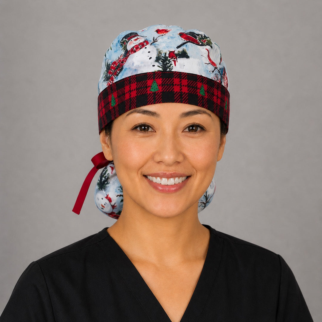Winter snowman ponytail surgical cap left three-quarter angle showing gathered ponytail pouch of snowmen and cardinals with red plaid band and red ribbon bow