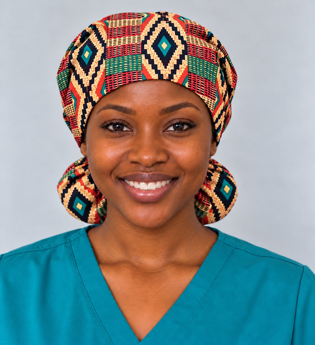 Front view of an XL Kente print ponytail scrub cap on a smiling nurse, with a black and teal stepped diamond centered over the forehead band