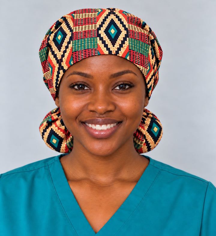 Front view of an XL Kente print ponytail scrub cap on a smiling nurse, with a black and teal stepped diamond centered over the forehead band