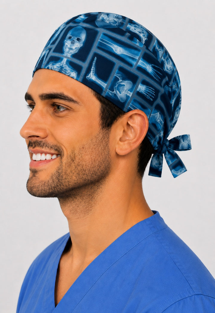 Left angle of radiology bone x-ray scrub cap on male tech — blue skeleton surgical tie-back cap, women-owned and handmade in the USA.