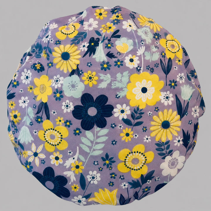Top-down detail of the yellow and white floral bouffant scrub cap — close-up of the lavender purple floral print on soft cotton